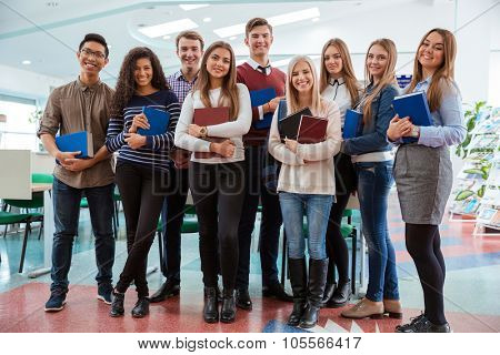Group of a happy students standing in classroom together and looking at camera