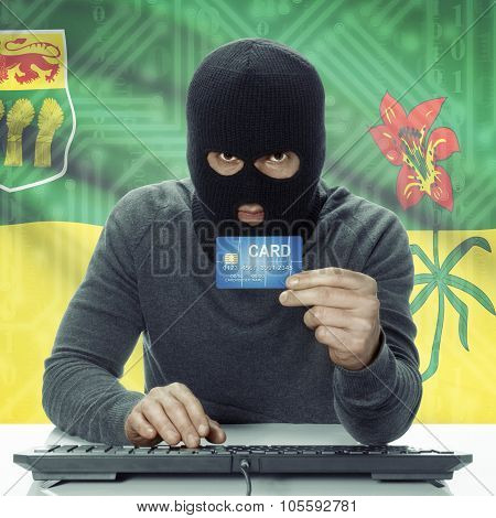 Dark-skinned Hacker With Canadian Province Flag On Background Holding Credit Card - Saskatchewan