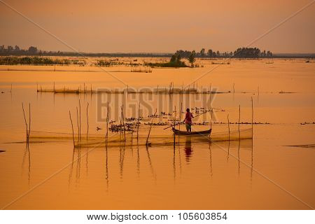 Fisher on boat in water season in sunrise in Dong Thap, Vietnam