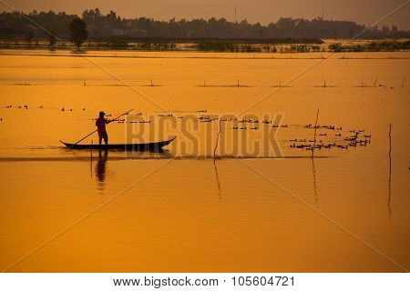 Fisher on boat in water season in sunrise in Dong Thap, Vietnam