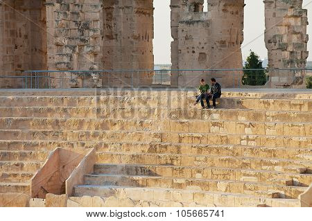 People sit at the stairs of the El Djem amphitheater in El Djem, Tunisia.