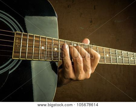 Closeup photo of an acoustic guitar played by a man.