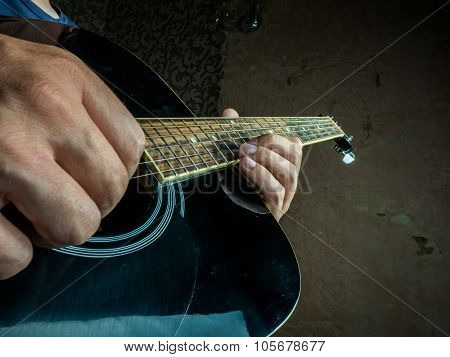 Closeup photo of an acoustic guitar played by a man.