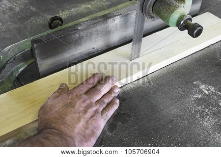 Carpenter Cutting Piece Of Wood With Bandsaw In Workshop