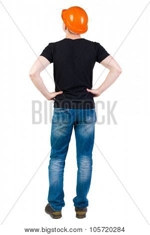 Backview of an engineer in construction helmet stands. Standing young guy. Rear view people collection.  backside view of person.  Isolated over white background. Engineer standing with hands on hips.