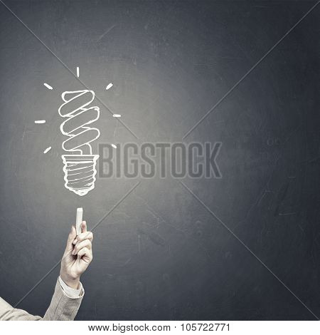 Human hand darwing light bulb as idea concept with chalk