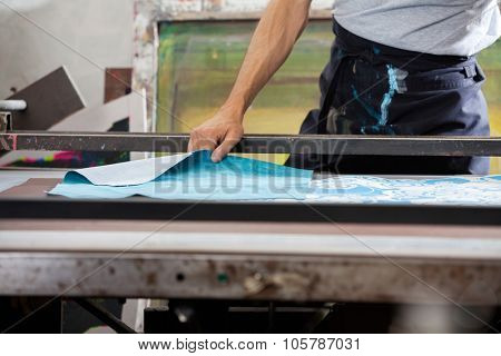 Midsection of male worker designing paper in factory