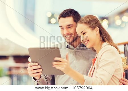 shopping, technology and people concept - happy couple with tablet pc taking selfie in mall or business center