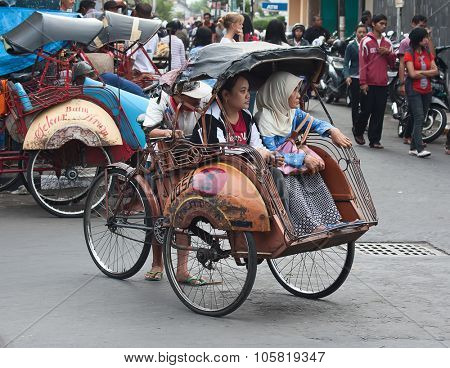 YOGYAKARTA - AUGUST 03: Traditional rikshaw transport on streets of Yogyakarta, Java, Indonesia on August 03, 2010. Bicycle rikshaw remains popular means of transport in many Indonesian cities.