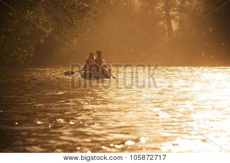 Two friends in canoe are swimming on the river in beautiful last evening light