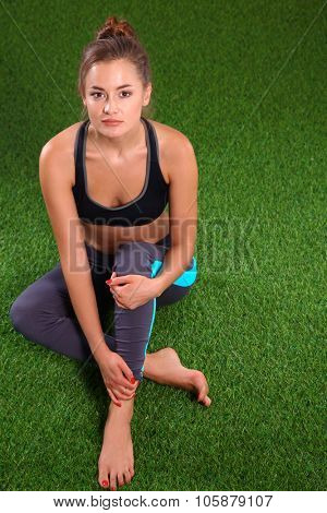 Beautiful young woman relaxing after exerscises on the grass 