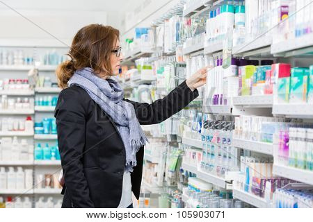 Mid adult female purchaser choosing product at pharmacy