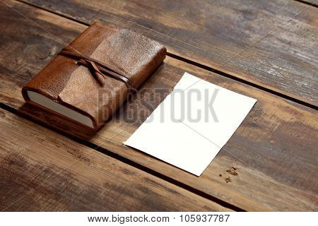 Notbook And A Sheet Of Paper On A Wooden Table From Aside