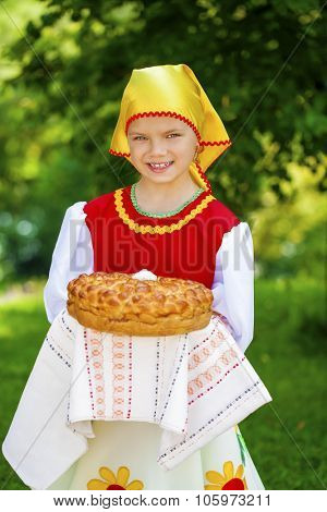 Little girl is dressed in the Russian national dress. She holds in his hands the fresh loaf. It is a custom to meet the guests.