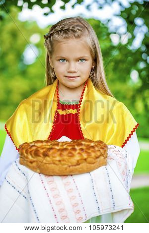 Little girl is dressed in the Russian national dress. She holds in his hands the fresh loaf. It is a custom to meet the guests.