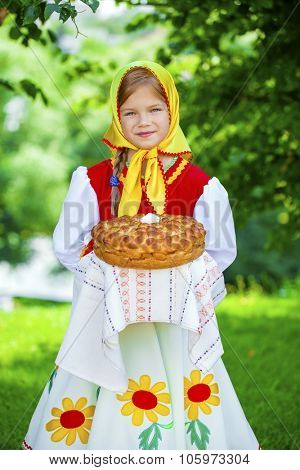 Little girl is dressed in the Russian national dress. She holds in his hands the fresh loaf. It is a custom to meet the guests.