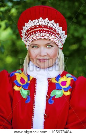 Close up young woman is dressed in the Russian national dress in summer park