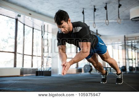 Sportsman wearing blue shorts and black t-shirt doing push-up with claping