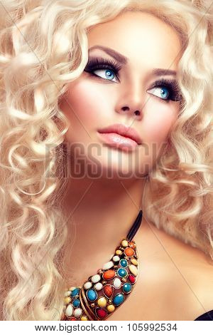 Beauty Girl With Healthy Long Curly Hair. Blonde Woman Portrait with blue eyes. Blond Wavy permed Hair and bright makeup, vivid make-up, smoky eyes and false eyelashes. Holiday make up. Perfect skin