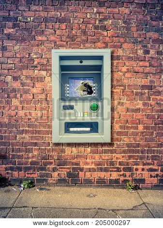 A Vandalized ATM Against A Grungy Red Brick Wall