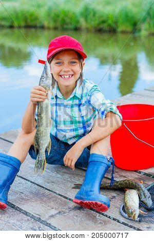 Happy cute boy enjoyed the fishing. Holding a big pike.