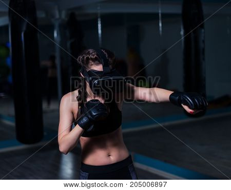 Young fighter boxer fit girl in VR glasses wearing boxing gloves in training. Boxing game in virtual reality 360 degrees. Futuristic gaming