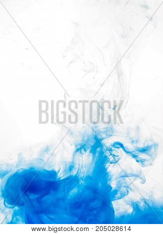 Ink swirl in water isolated on white background. The paint in the water. Soft dissemination a droplets of blue ink in water close-up. Abstract background. Soft focus.