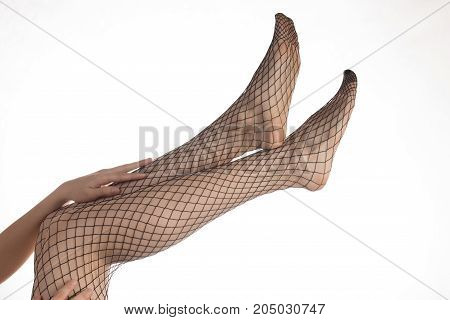 Sexy slender girl with beautiful legs in pantyhose mesh and black lacy panties over white background