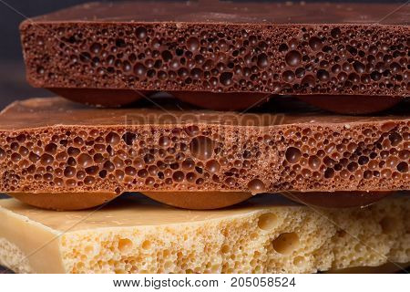 stack of different kind porous chocolate pieces on a dark background.