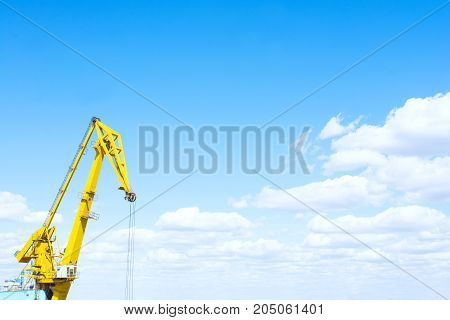 Harbor crane against the blue cloudy sky.