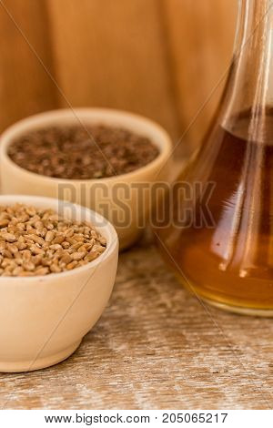 Close up wooden bowl with wheat grains and seed oil in decanter organic food concept