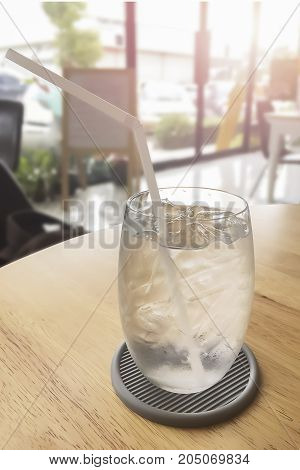 Closeup on Purity Cold fresh mineral water with ice in clear glass on wooden table during hot summer day.