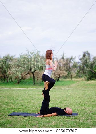Beautiful woman and girl practise yoga pose outside. Women doing stretching workout in park outdoors at sunset.