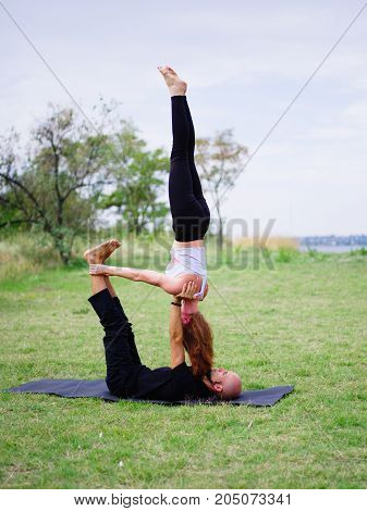 Beautiful woman and girl practise yoga pose outside. Women doing stretching workout in park outdoors at sunset.