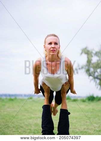 Girl in white shirt exercises yoga outdoor, on green grass.