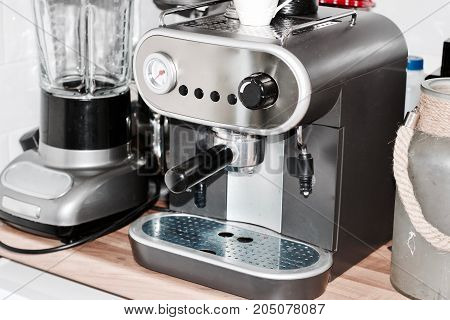 Big silver coffee machine in the kitchen near big glass jar and other kitchen stuff.