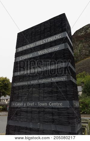 Tourist information street sign giving directions made out of slate in the historic Welsh mining town of Blaenau Ffestiniog in English and Welsh languages
