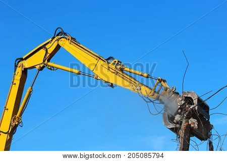 Large yellow demolition crane dismantling a building.