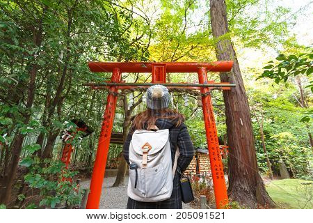 KYOTO JAPAN - NOVEMBER 23 2016 Hipster young girl with backpack enjoying shrine. Tourist traveler on background view mockup. Hiker looking temple in trip in Arashiyama Tokyo Japan.