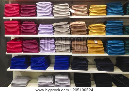 Rows of folded colorful clothes in a shop