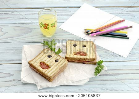 Children's food. Hot sandwiches and a glass of juice on a wooden table closeup