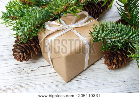 Christmas gift box on the white wooden table background spruce branch pine cones frame top view space for text.