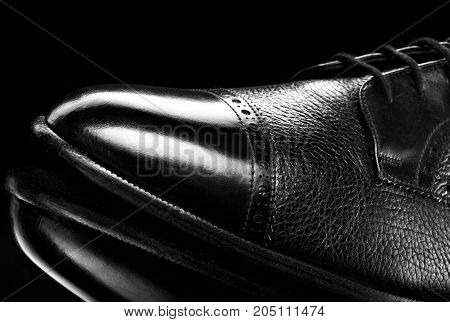 Black oxford polished shoes on black miror background.Shoes shine. Close up.