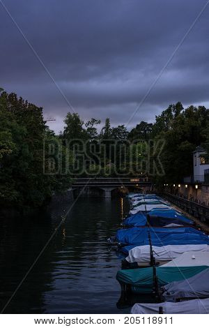 small boats in canal at night with cloudy sky and raincovers for fishing and sailing
