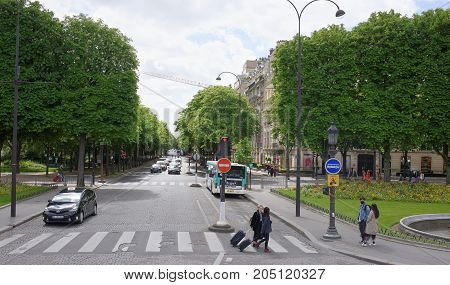 Paris; France- May 01; 2017: People walk along the Champs Elysees and Franklin Delano Ruzvelt Avenue. On the avenue the car is moving
