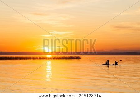 Silhouette Of Two Canoeists On Lake During Sunset