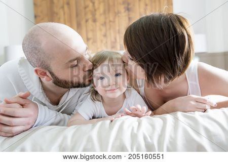A Family with child. Happy parents playing with baby on bed