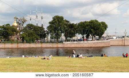 SAINT PETERSBURG, RUSSIA - AUGUST 24, 2017: People resting on the banks of the Neva river at the Peter and Paul fortress on background of Church Holy Trinity chapel and the masts of the Frigate.