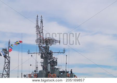 Top part of big military battleship with towers masts flags of coloring and antennas