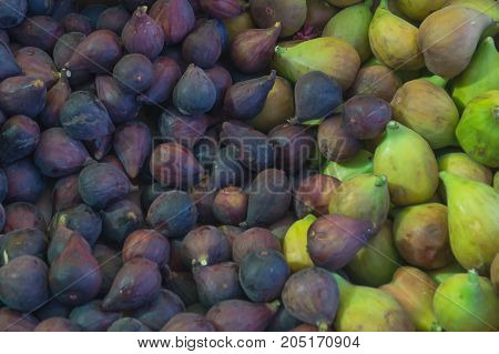 Dark blue and green figs in the market as a background